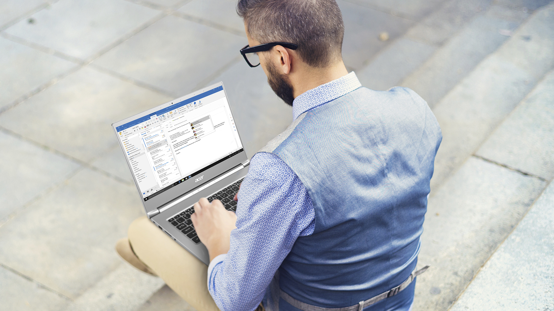 Hombre sentado en escaleras utilizando una laptop Acer, trabajando en una aplicación de software.