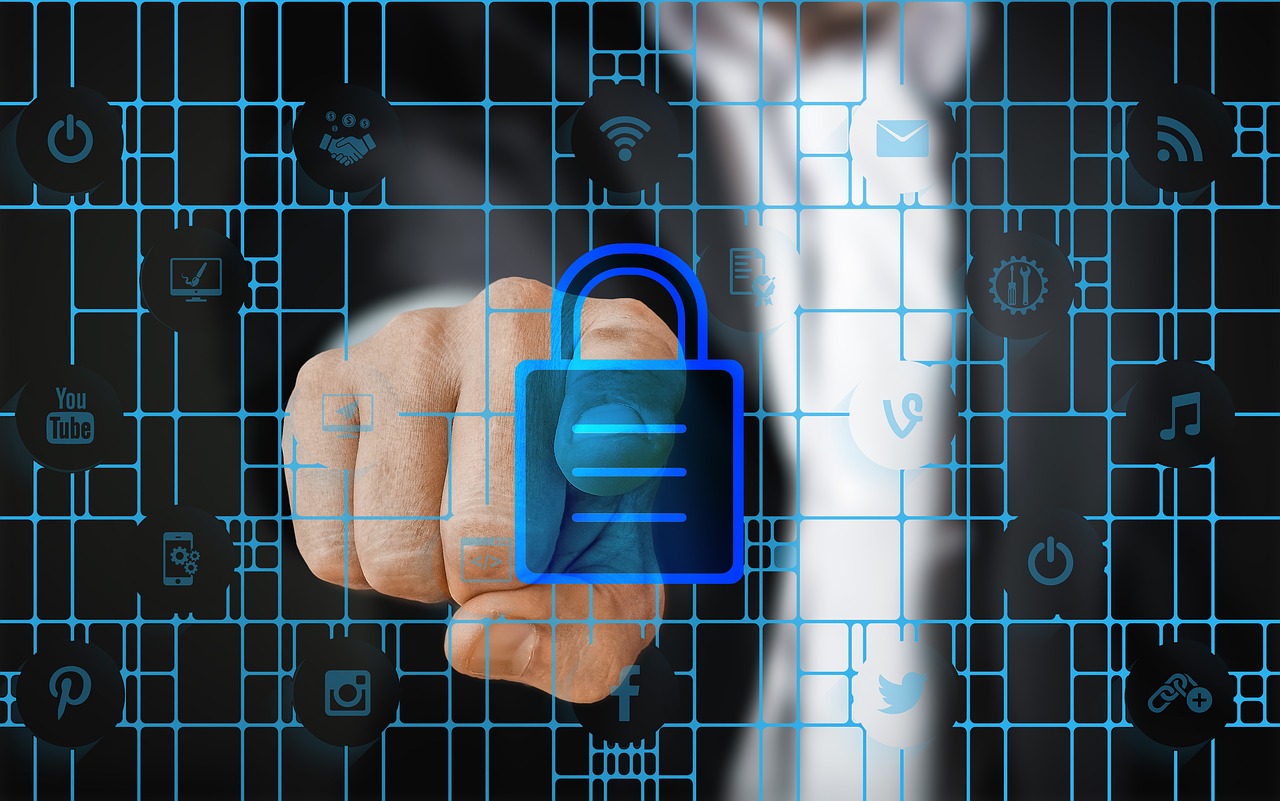 Una mano presionando un icono de candado sobre un fondo de símbolos de redes sociales y tecnología, representando la ciberseguridad.