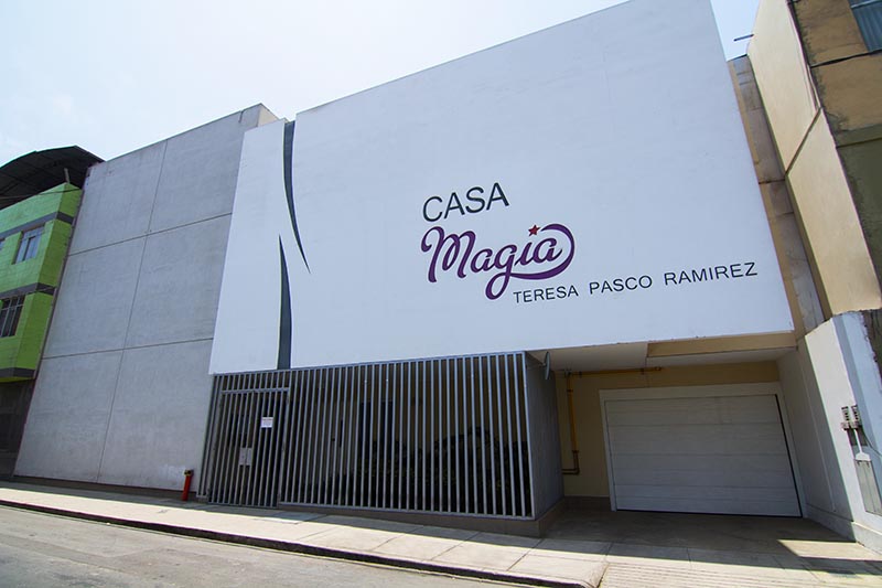 Fachada del edificio Casa Magia, con el nombre visible en la pared y una puerta de entrada con rejas.