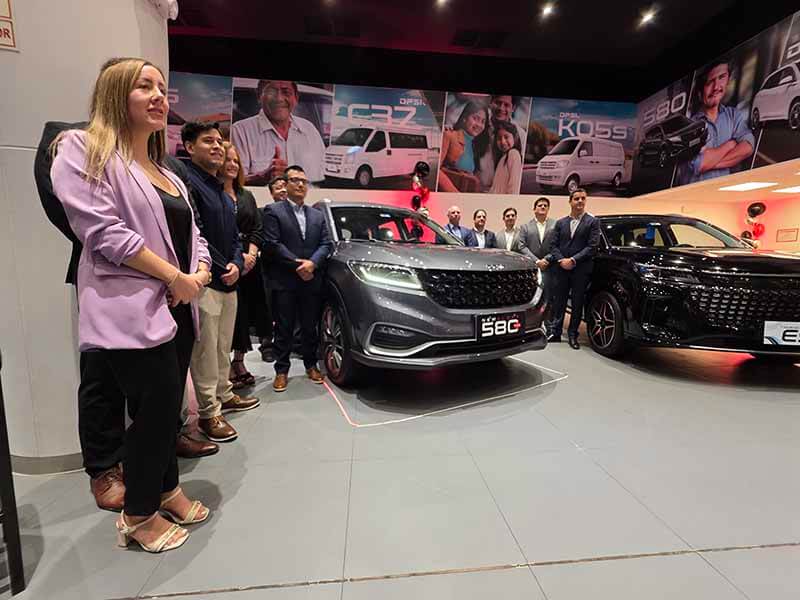 Inauguración de la tienda DFSK en Surquillo, con asistentes posando frente a un SUV Glory 580 Plus y un vehículo eléctrico E5 en un showroom moderno.