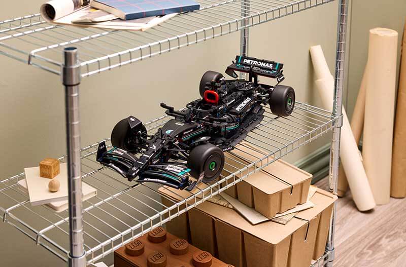 Modelo de automóvil de carrera de LEGO Mercedes-AMG Petronas F1® W14 en una estantería, rodeado de objetos de diseño y coleccionables.