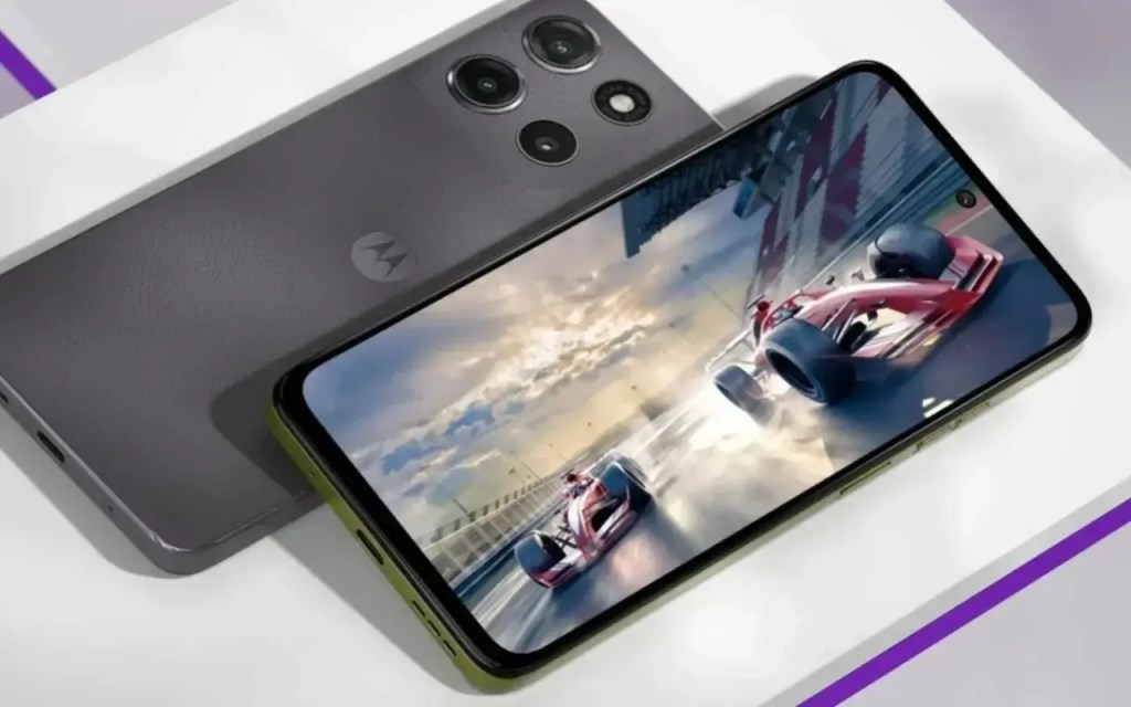 Imagen del smartphone Motorola moto g15 mostrando su pantalla Full HD+ con un simulador de carreras, reposando sobre una superficie blanca con textura.