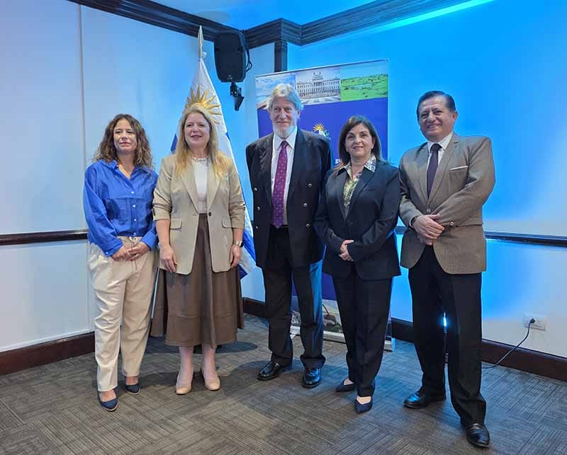 Grupo de personas posando frente a una pared iluminada con un banner de Uruguay, en una presentación de turismo en el hotel Meliá de Lima.