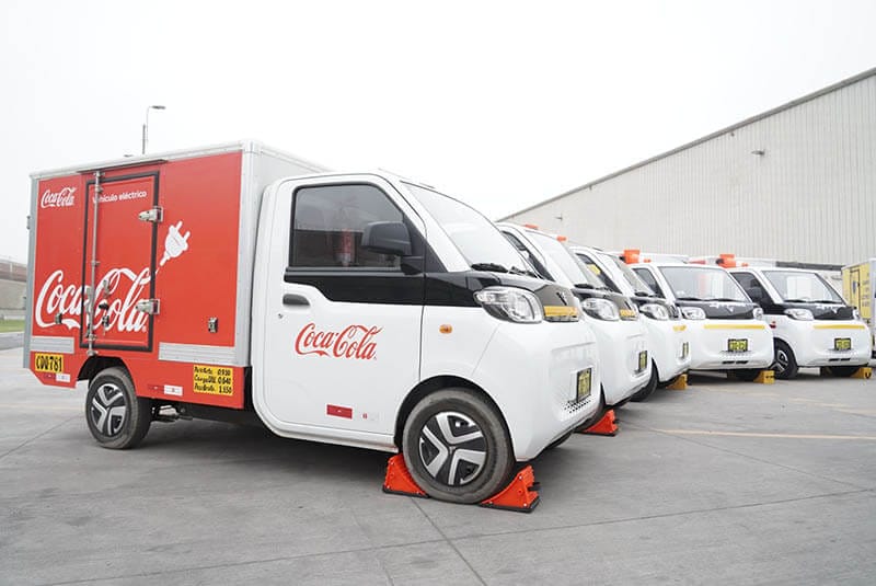 Camiones eléctricos de Coca-Cola en un estacionamiento, diseñados para operaciones logísticas sostenibles.