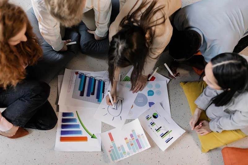 Grupo de personas colaborando en un proyecto sobre gráficos y estadísticas en un ambiente de trabajo creativo.