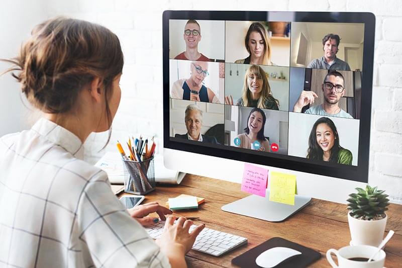 Una persona participando en una videoconferencia en una computadora de escritorio, mostrando a varios participantes en la pantalla.