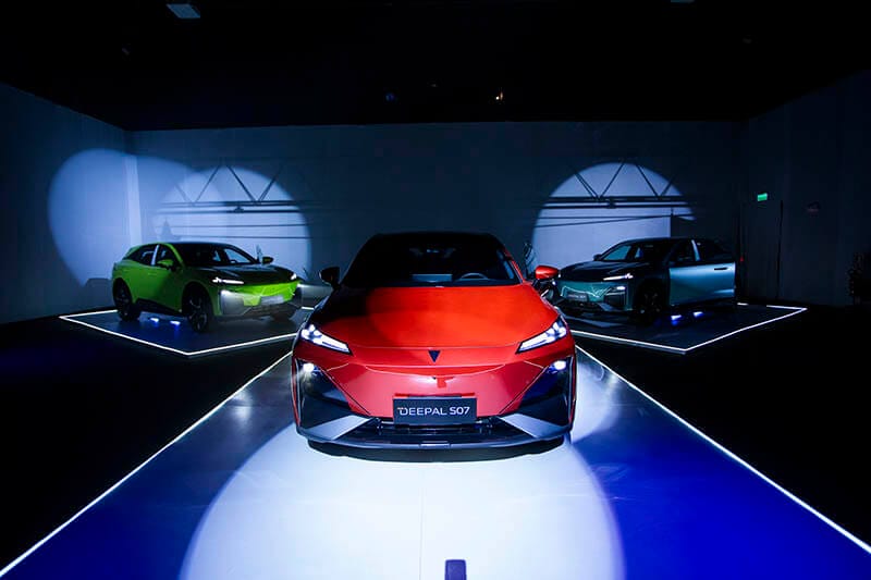 SUV híbrido-eléctrico Deepal S07 de Changan, en color rojo, con iluminación dramática y otros dos modelos en el fondo: uno verde y otro plateado.