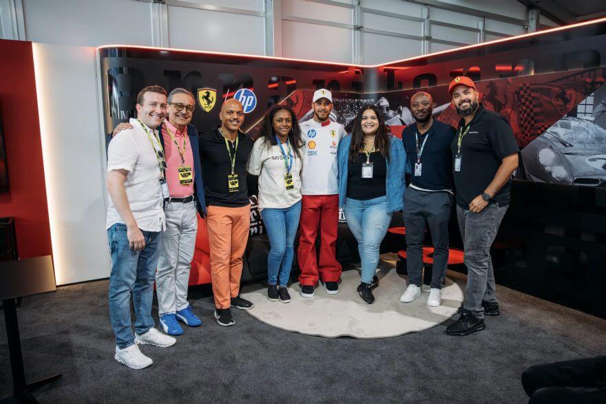 Grupo de jóvenes posando con un miembro del equipo de Scuderia Ferrari en el circuito del Gran Premio de F1 en Miami, durante el anuncio de la colaboración entre Mission 44 y HP Inc.