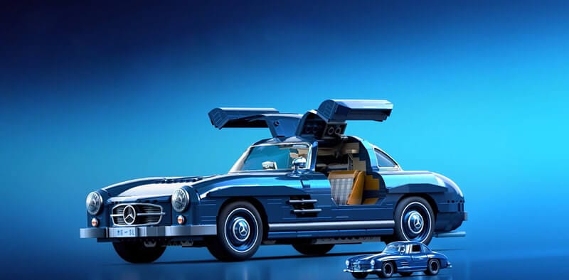Modelo de un auto Mercedes-Benz 300 SL a escala, con puertas de ala de gaviota abiertas y un auto metálico pequeño al lado, sobre un fondo azul.