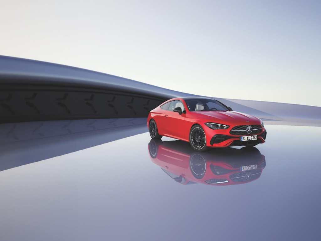 Mercedes-Benz CLE 300 Coupé KIT AMG en un fondo minimalista, mostrando su diseño deportivo en color rojo con detalles en negro, reflejándose en una superficie pulida.