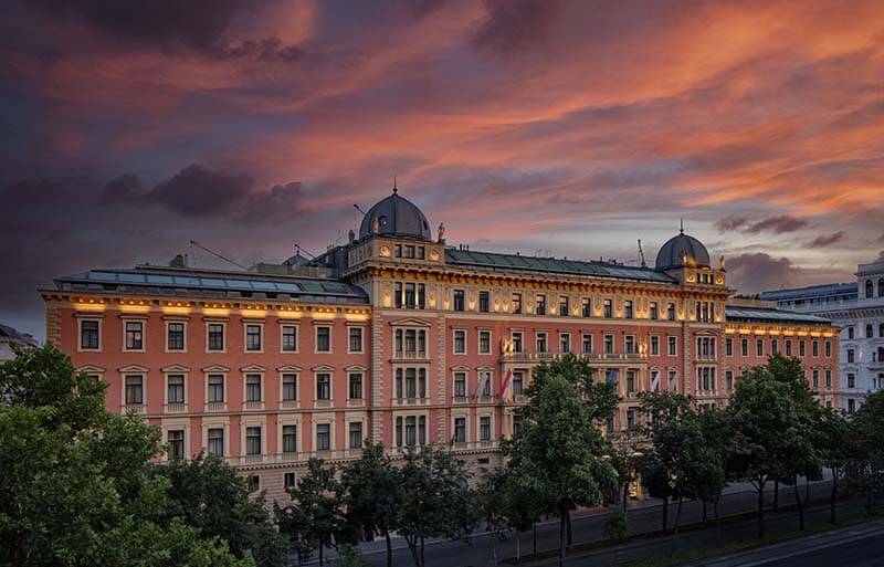 Edificio elegante de múltiples pisos con detalles arquitectónicos en un atardecer colorido.