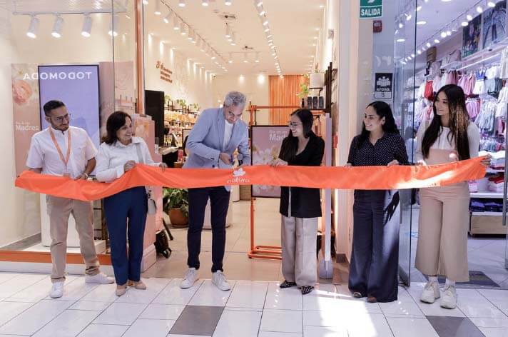 Ceremonia de inauguración de la tienda Natura en Arequipa, con un grupo de personas cortando una cinta naranja en la entrada del establecimiento.