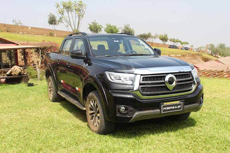 Pickup GWM Poer 2.4 Automática, color negro, estacionada en un paisaje verde con árboles al fondo, destacando su diseño moderno y robusto.