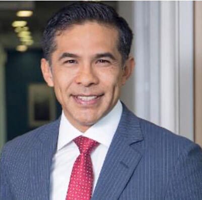 Retrato de Erick Pilco, nuevo Territory Manager de OSC Top Solutions en Perú, luciendo una chaqueta azul y una corbata roja, sonriendo frente a una oficina.