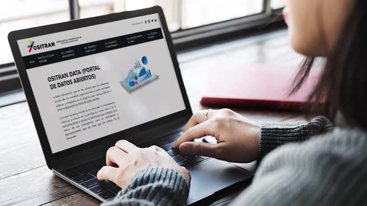Persona utilizando un laptop que muestra la plataforma Ositrán Data, un portal de datos abiertos sobre infraestructuras de transporte.