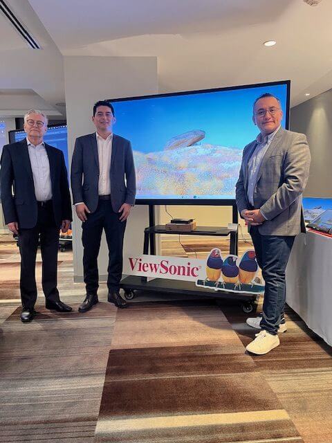 Tres personas posando frente a un monitor con la marca ViewSonic en un evento de presentación de productos.