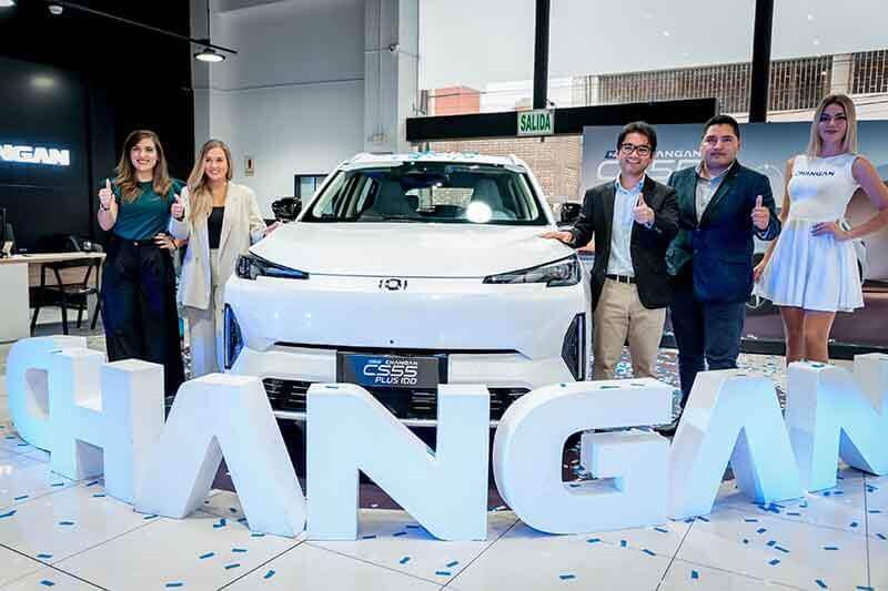 Evento de lanzamiento de la SUV híbrida Changan CS55 PLUS iDD, con cuatro personas posando junto al vehículo y letras de la marca en el fondo.
