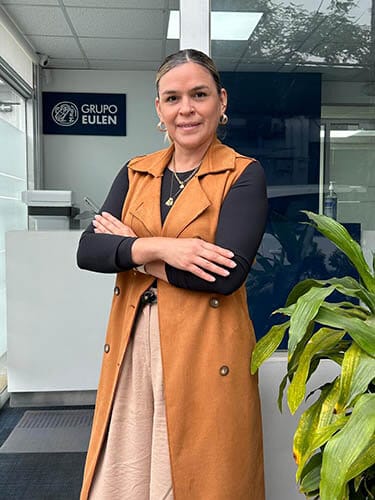 Maria Elena Iturrizaga Vidal, nueva Gerente de Limpieza, Medio Ambiente y Servicios Auxiliares de Grupo EULEN, posando con los brazos cruzados en una oficina con plantas y un logo visible de la empresa.