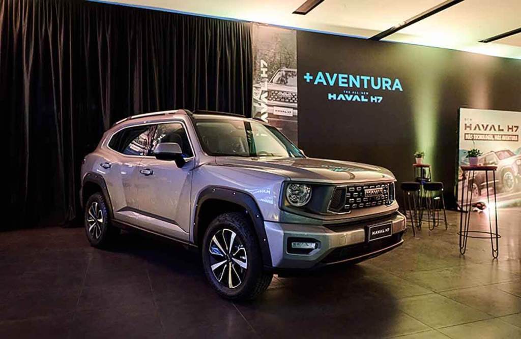 Imagen de la nueva SUV Haval H7, presentada en un evento de lanzamiento, destacando su diseño robusto y moderno, en un entorno interior con fondo oscurecido y elementos de presentación.