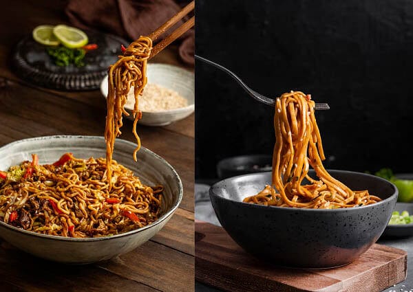 Un plato de tallarines instantáneos Indomie con vegetales y cucharas en un bol de cerámica, junto a un segundo bol con tallarines siendo levantados con un tenedor en un fondo oscuro.