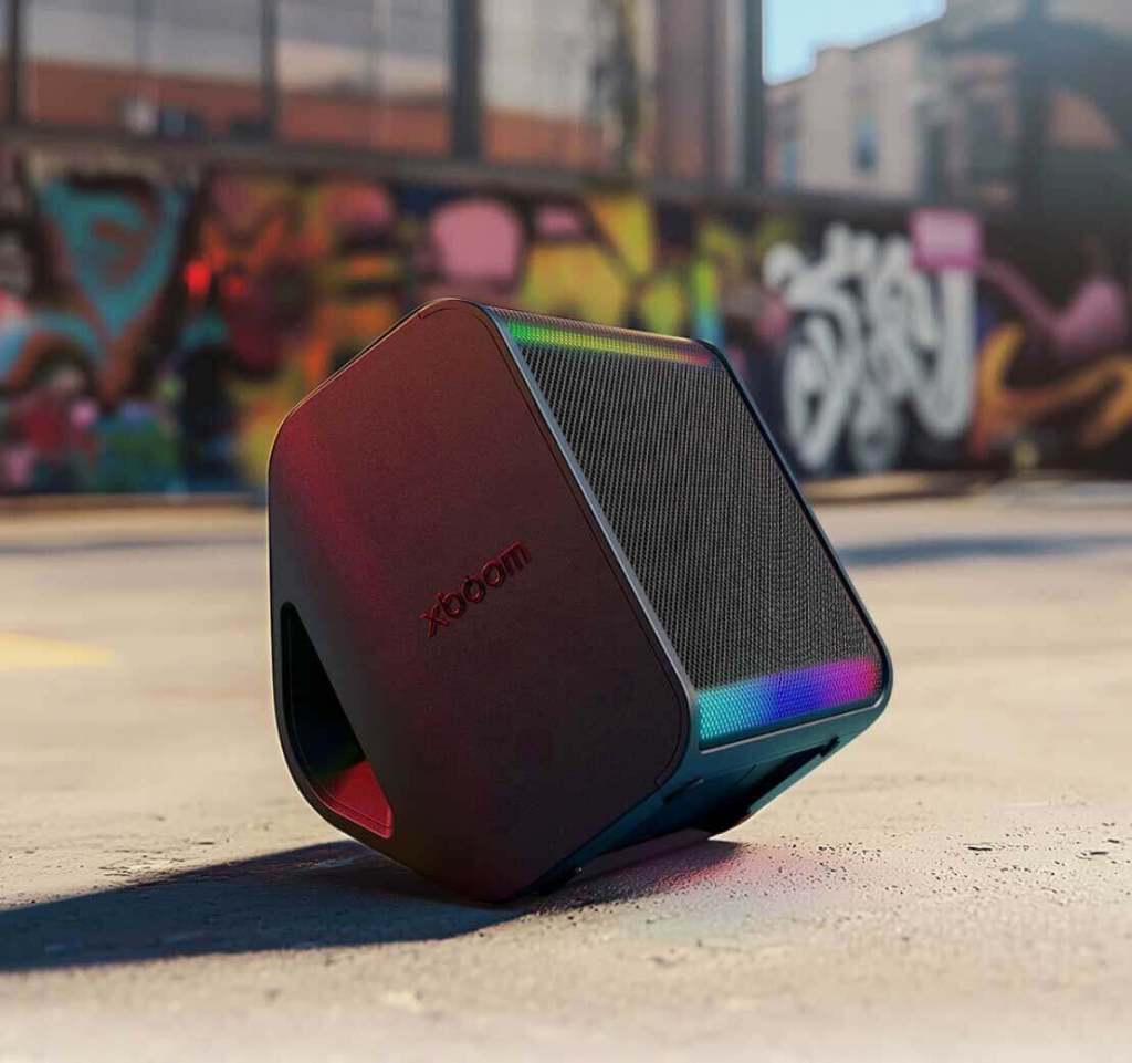 Parlante Bluetooth xboom de LG con diseño moderno y colores vibrantes, colocado sobre una superficie urbana con un fondo de arte callejero.
