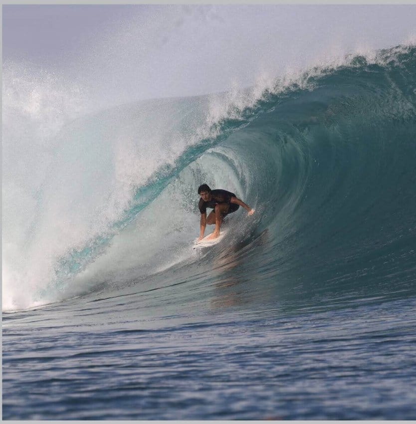 Surfista peruano ejecutando una maniobra en una ola durante una competencia de surf.