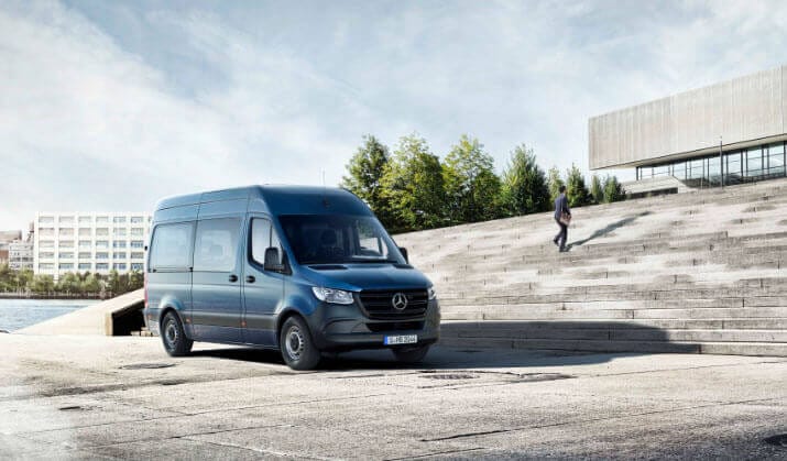 Van Mercedes-Benz Sprinter estacionada en un área urbana con escalones y un paisaje verde al fondo