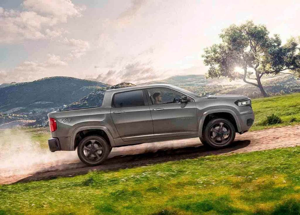 Una camioneta robusta y moderna, circulando por un terreno off-road con un paisaje montañoso de fondo.