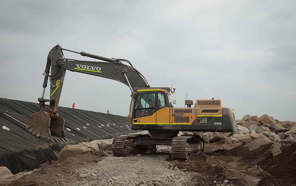 Excavadora Volvo trabajando en un sitio de construcción con materiales y rocas alrededor.