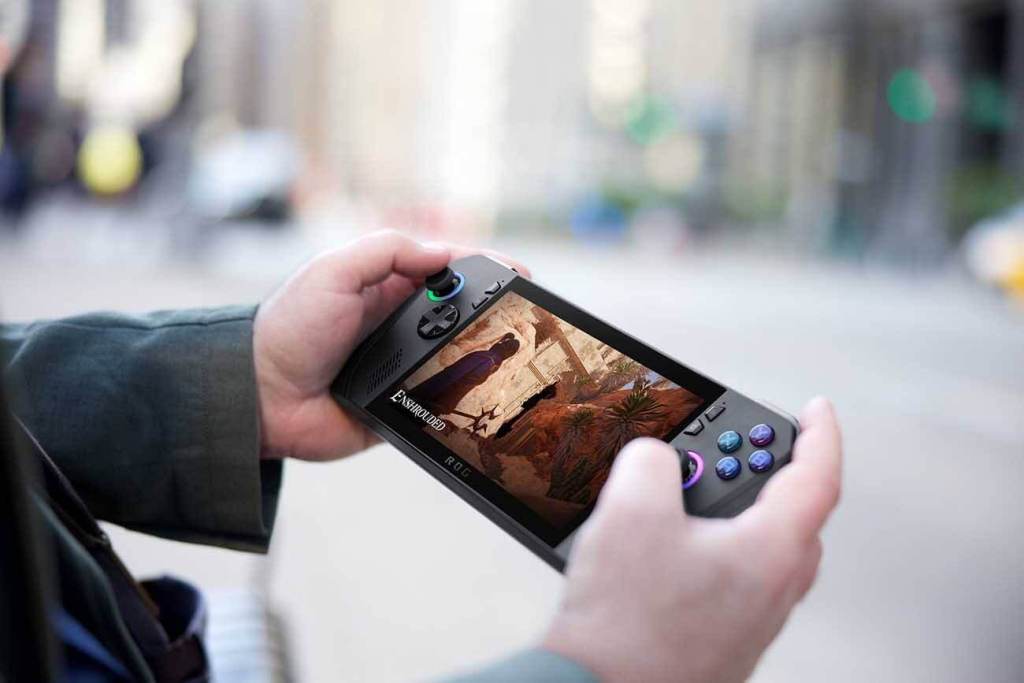Persona sosteniendo una consola portátil de juegos ROG Ally en la calle, mostrando una pantalla con gráficos de un videojuego.