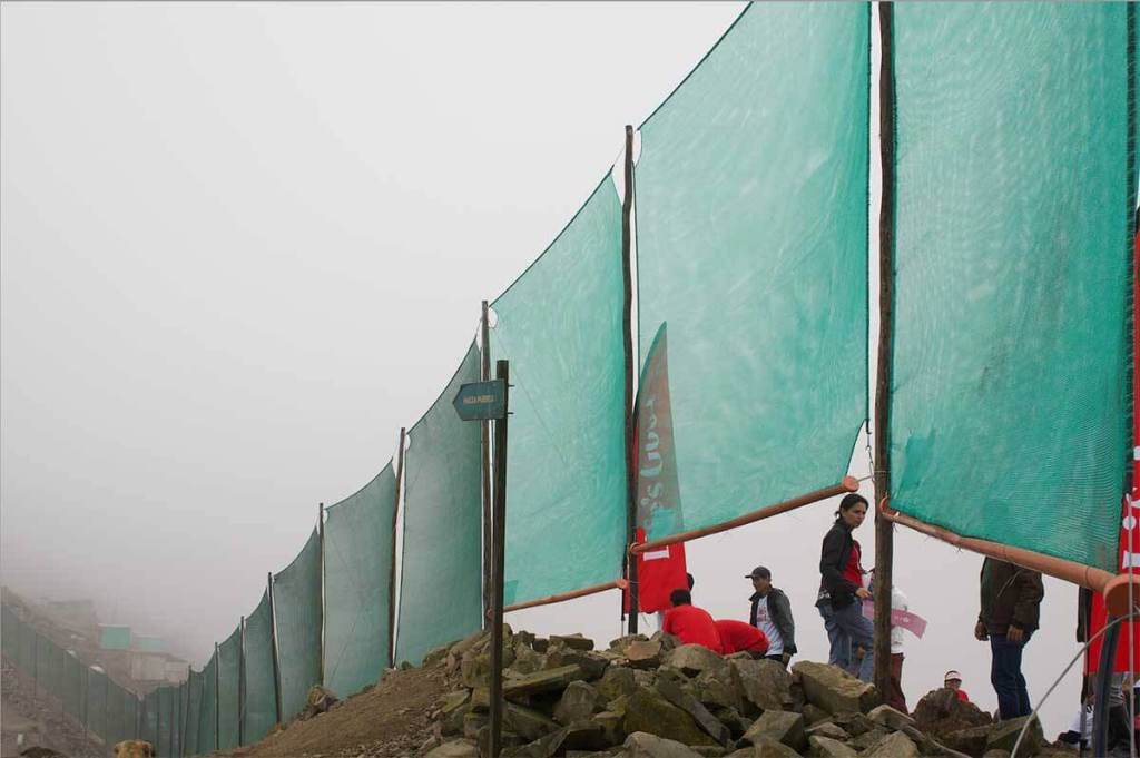 Paneles atrapanieblas instalados en un paisaje neblinoso, con personas trabajando en el área.