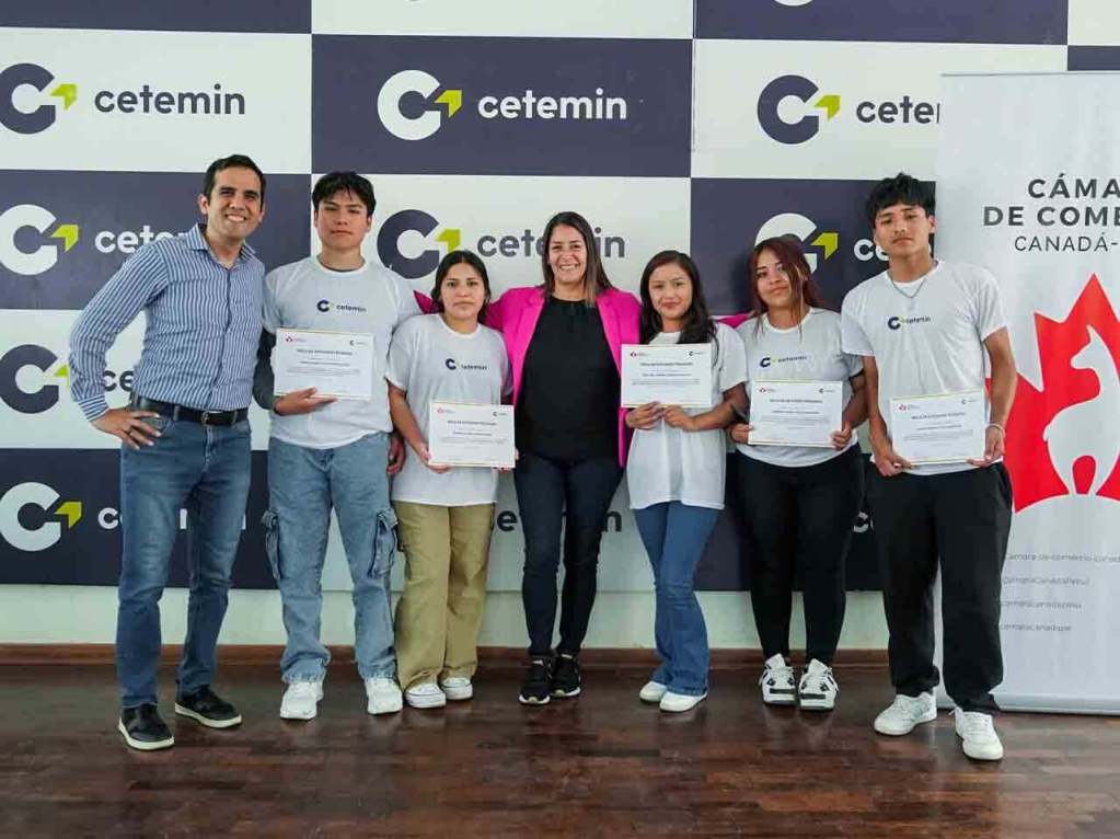 Un grupo de seis personas posando con certificados en un evento relacionado con becas de CETEMIN, en un entorno de oficina con un fondo de logotipos de CETEMIN y la Cámara de Comercio Canadá Perú.