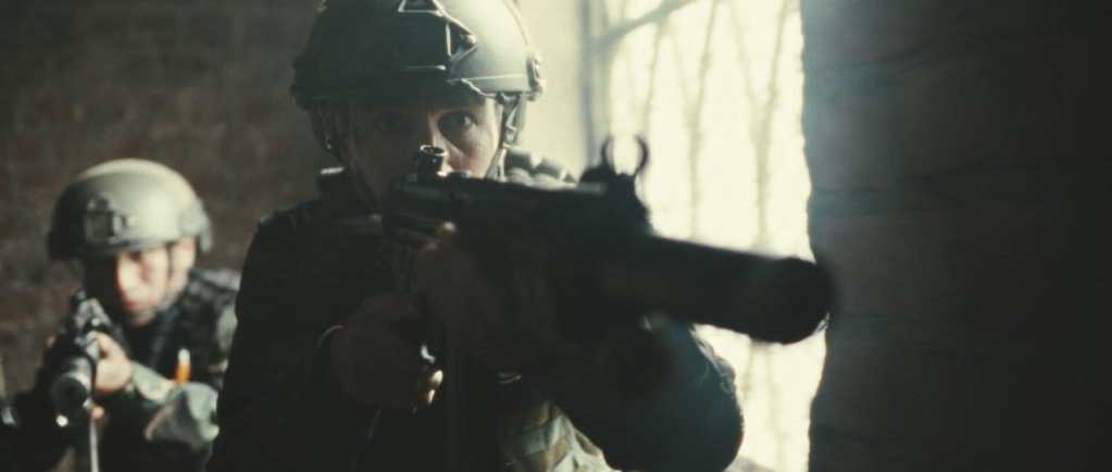 Escena de acción de la película 'Chavín de Huántar, el rescate del siglo', mostrando a un soldado con un arma en la mano durante un operativo militar.