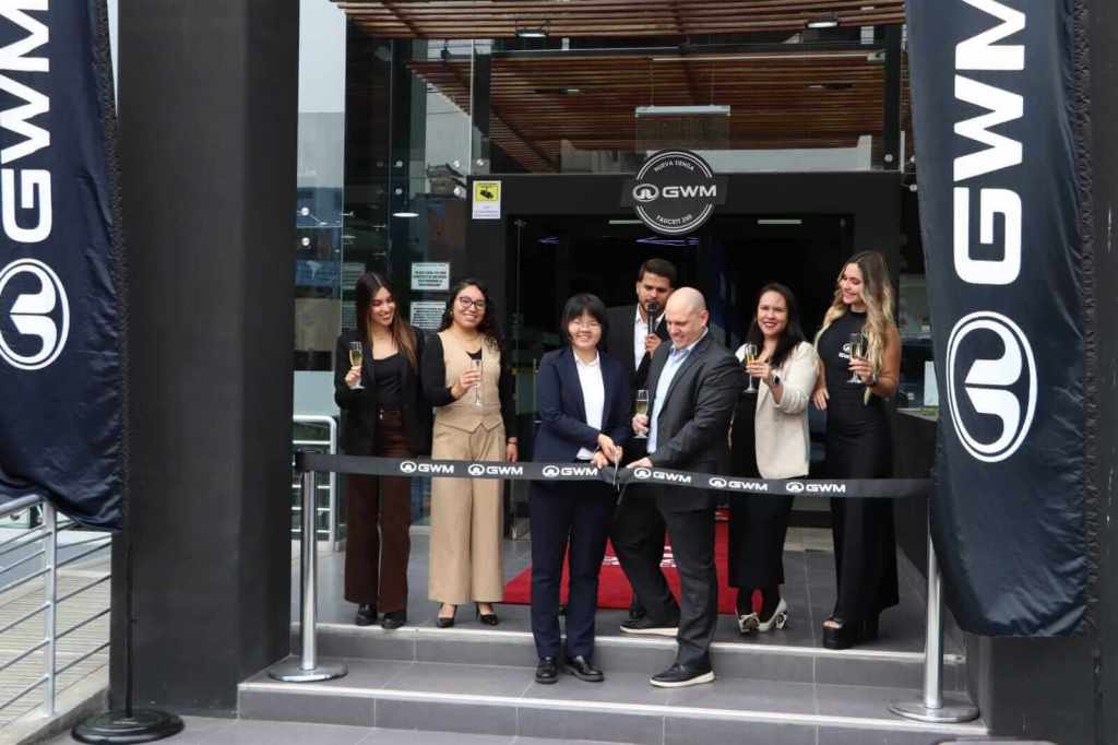 Inauguración de la nueva tienda GWM en San Miguel, con varias personas sosteniendo copas de celebración frente a la entrada.