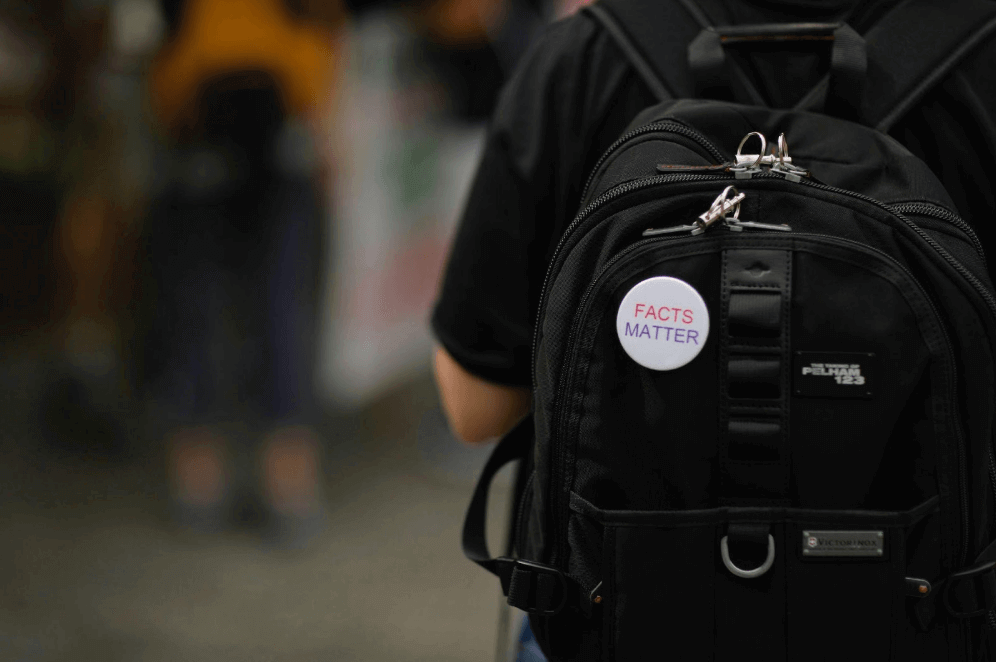 Una mochila negra con un distintivo con el texto 'FACTS MATTER'.