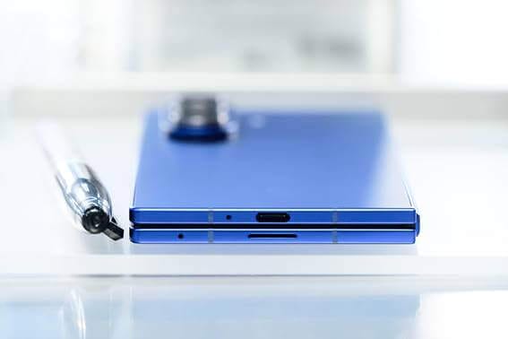 Vista superior del Galaxy Z Fold7 en color azul, mostrando su diseño delgado y puertos de conexión, junto a un bolígrafo para referencia de escala.