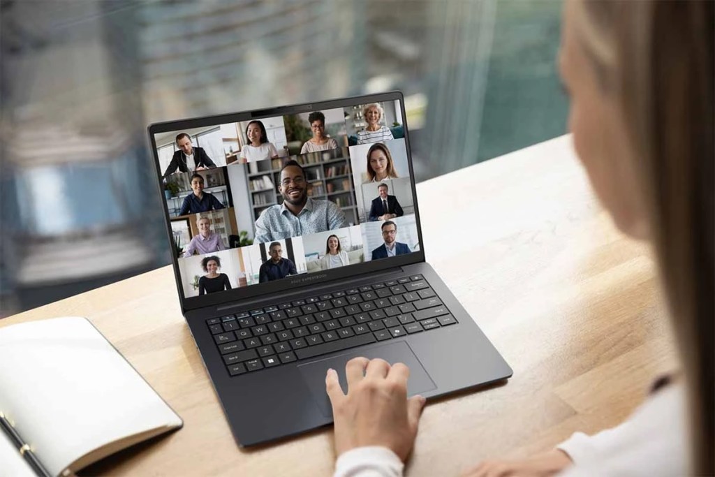 Una persona usando una computadora portátil en una videoconferencia con varios participantes en pantalla.
