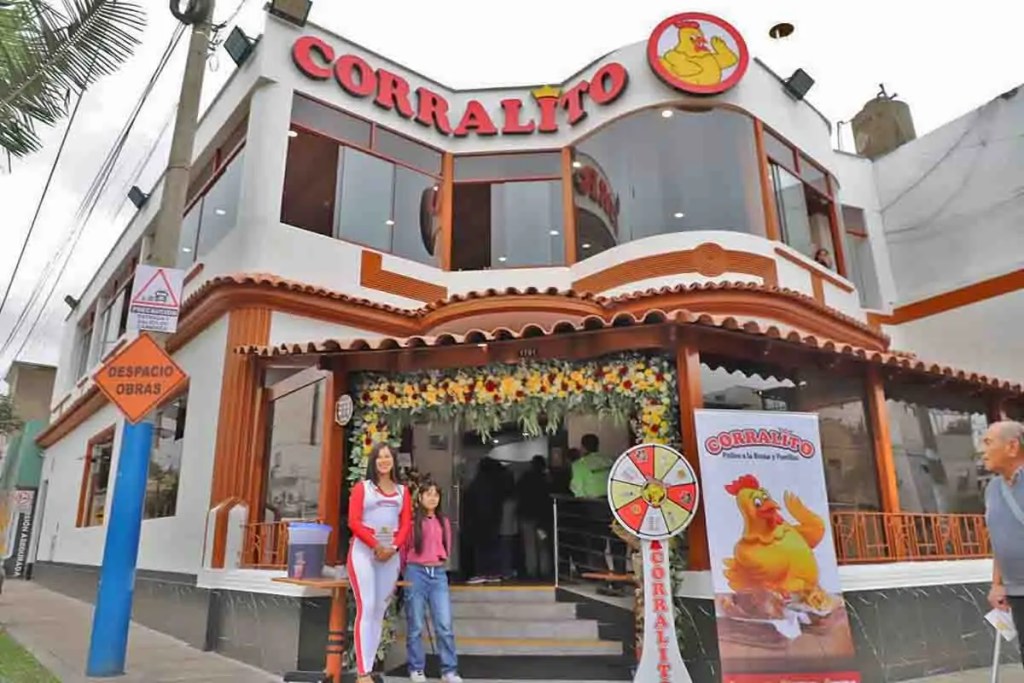 Fachada del nuevo local N° 60 de la cadena de pollerías y parrillas CORRALITO en Lince, con personal, un cartel de la marca y decoración floral.