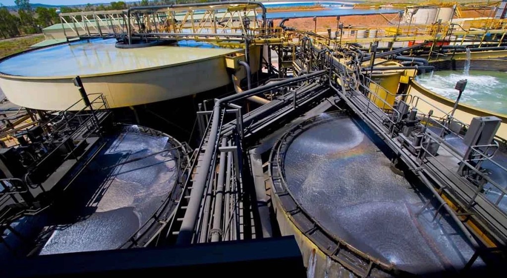 Vista aérea de un sistema de flotación en una planta de procesamiento de minerales, mostrando tanques circulares y tuberías interconectadas.