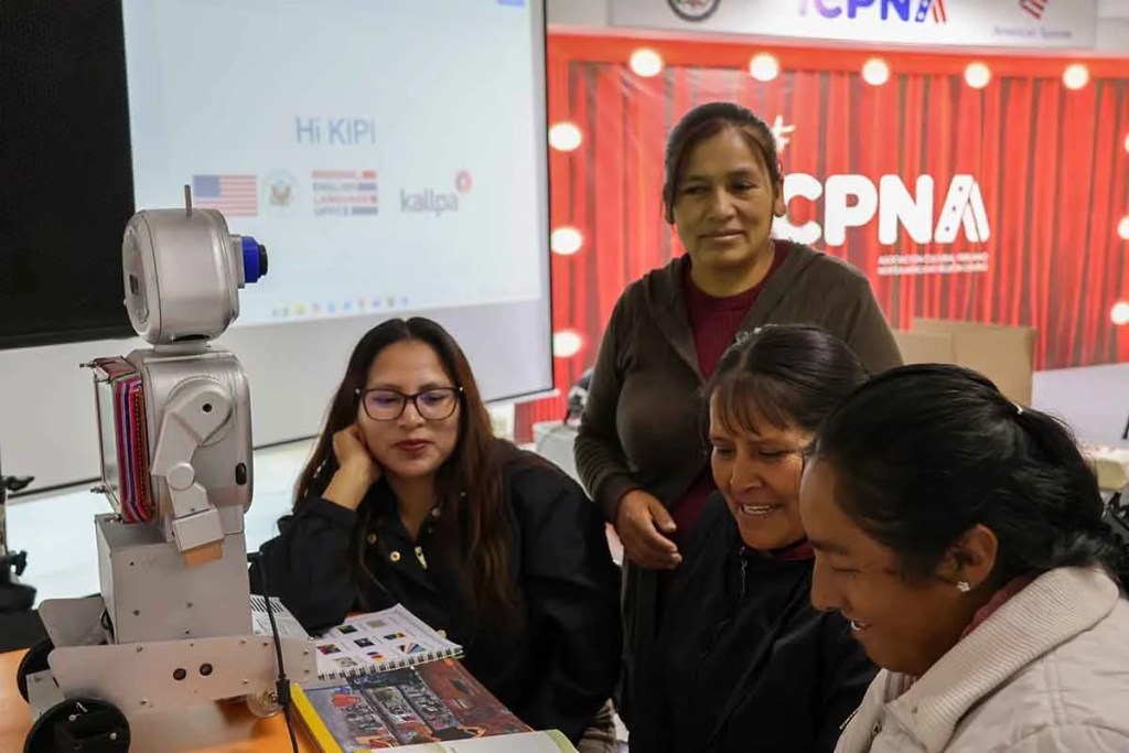 En una capacitación, cuatro docentes observan y interactúan con el robot Kipi, diseñado para enseñar inglés en comunidades rurales.