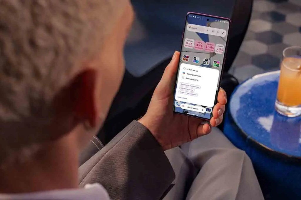 Una persona sosteniendo un smartphone Motorola que muestra la interfaz de Microsoft Copilot Vision con opciones para interactuar, mientras se encuentra en un ambiente moderno y elegante.