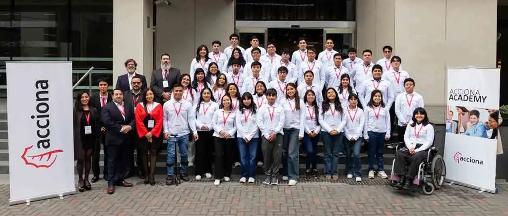 Grupo de jóvenes participantes de la cuarta edición del programa ACCIONA Academy en Perú, posando para una foto grupal con banderas de la empresa.