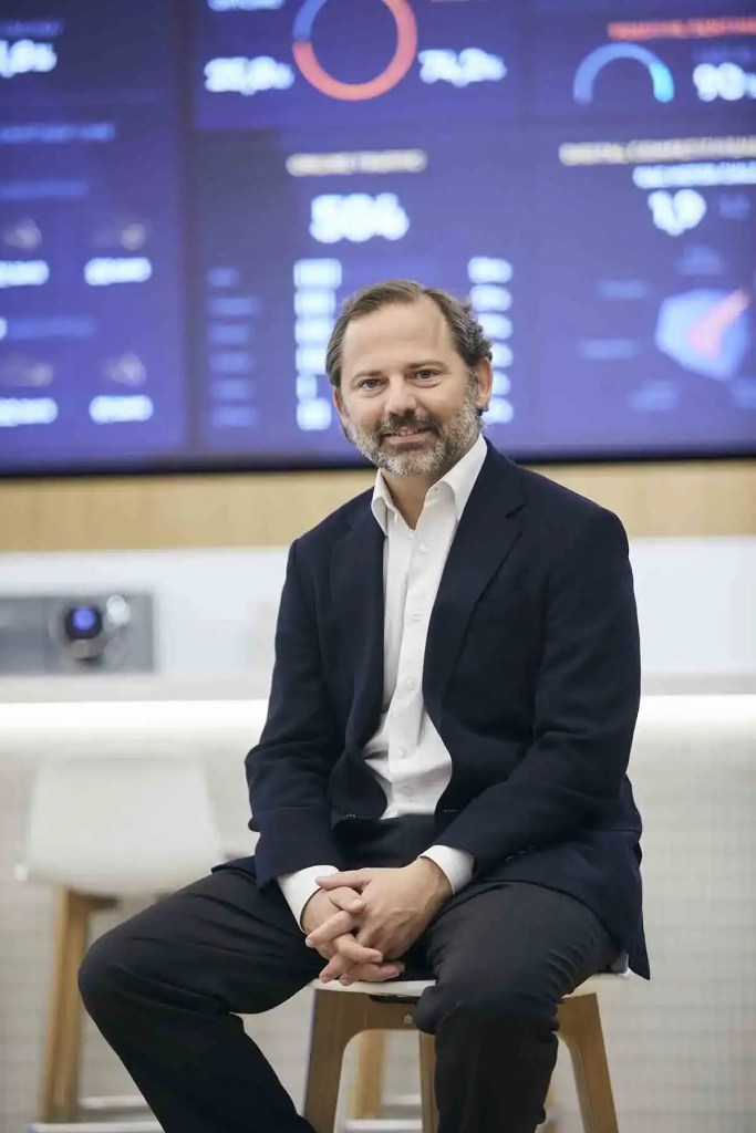 Ignacio Enciso, nuevo consejero delegado de Astara, posando en un entorno profesional con una pantalla digital de fondo que muestra gráficos y datos.