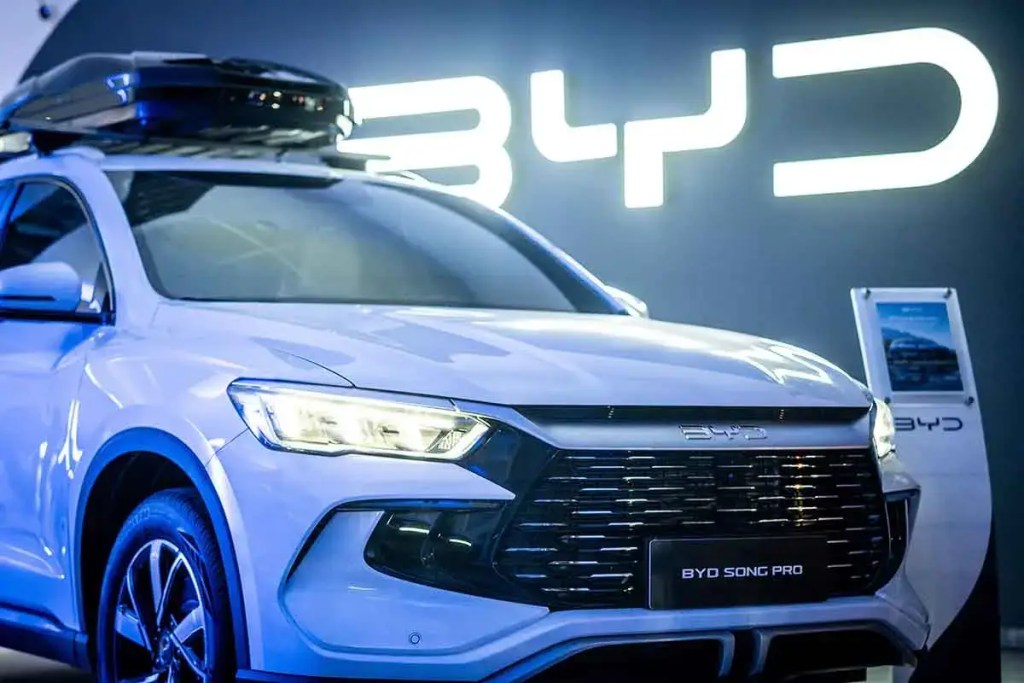 Imagen de un vehículo eléctrico BYD Song Pro en un evento promocional, con un fondo iluminado que muestra el logo de BYD.