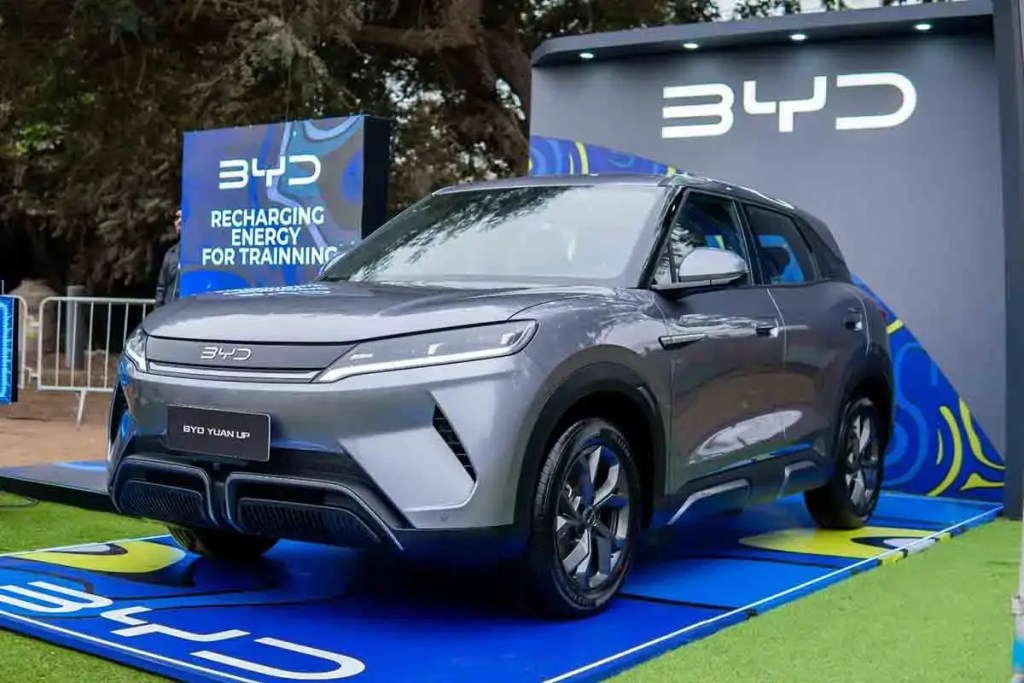 Vehículo eléctrico BYD Yuan UP presentado en el Lima Training Fest 2025, con un fondo colorido y la frase 'Recharging Energy for Training'.