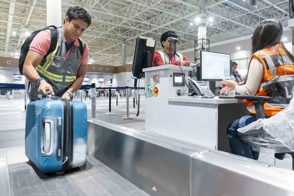 Pasajero haciendo el check-in con una maleta en un aeropuerto moderno.
