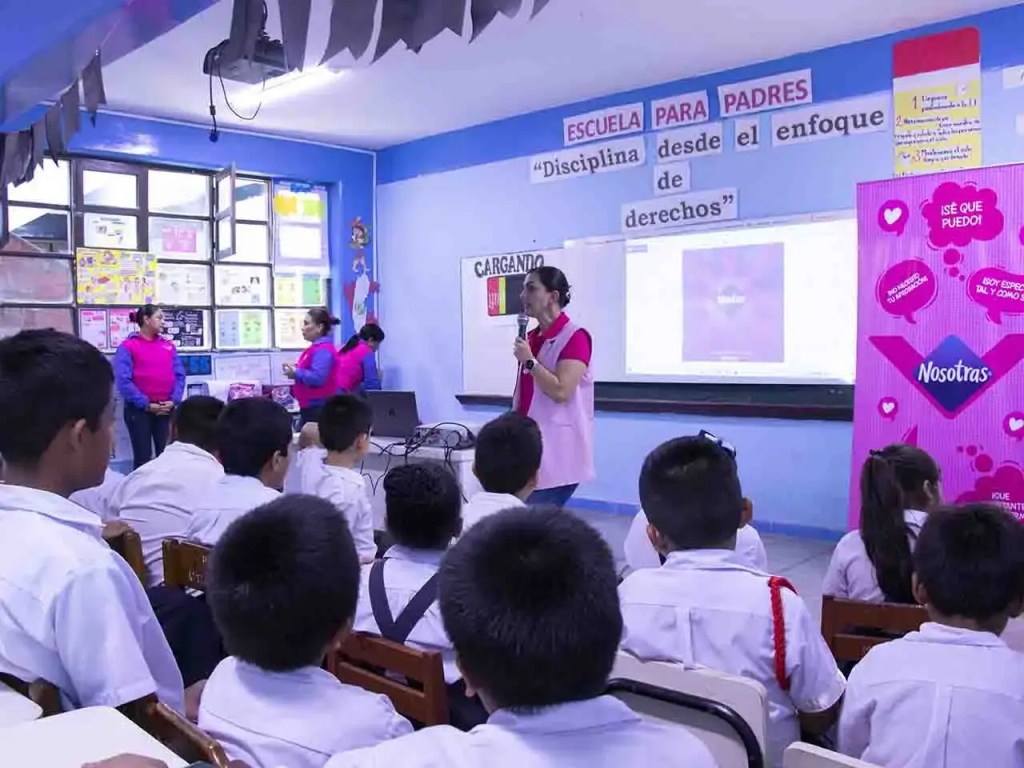 Una charla educativa sobre higiene menstrual en un aula escolar, con estudiantes sentados y representantes de la marca Nosotras en la parte delantera.