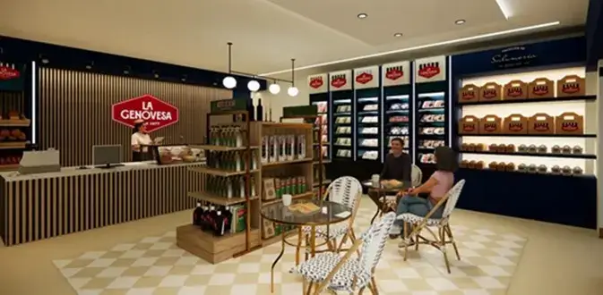 Interior de una tienda de La Genovesa, mostrando estanterías con productos gourmet y embutidos, con un espacio para sentarse donde dos personas conversan.