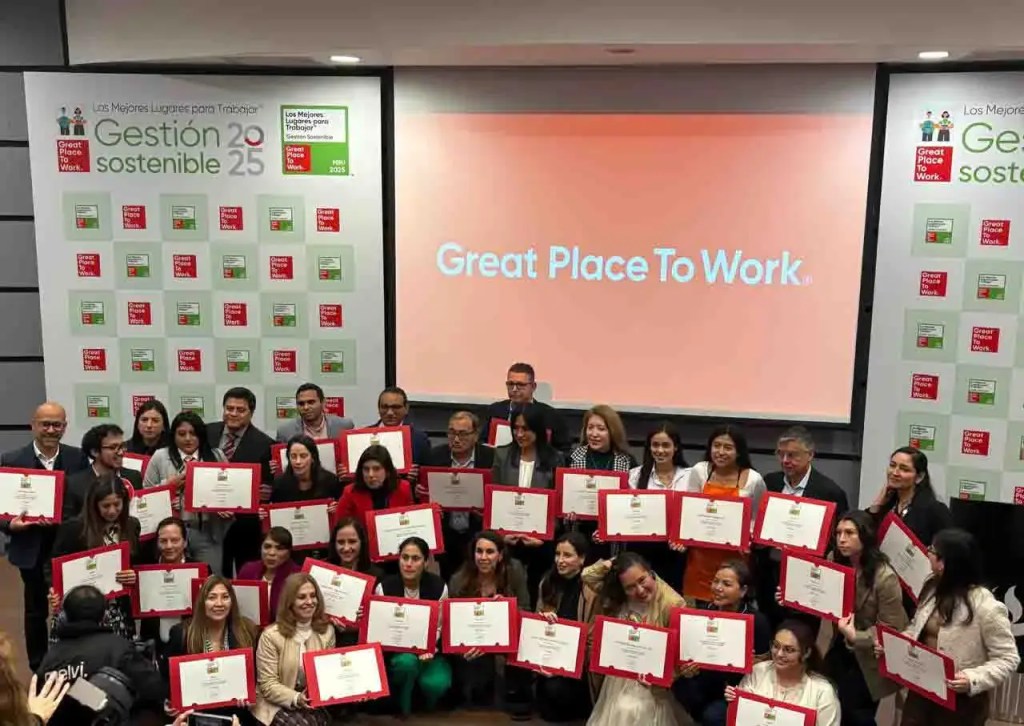 Grupo de empleados de Pamolsa posando con certificados en un evento de reconocimiento de Great Place to Work Perú, con un fondo que muestra el logo de Great Place to Work.