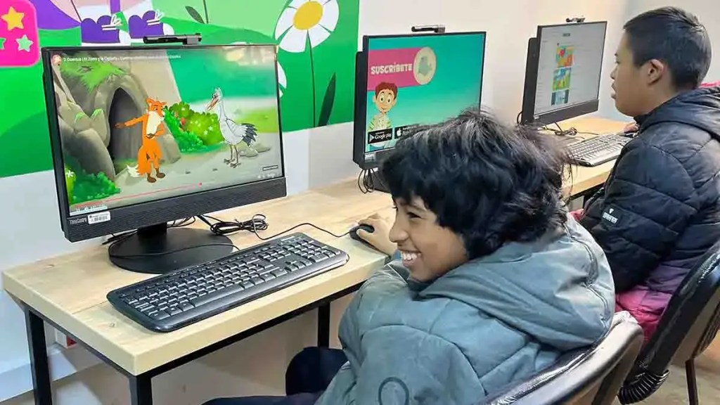 Niños usando computadoras en el laboratorio de cómputo de Primax, disfrutando de contenido educativo.